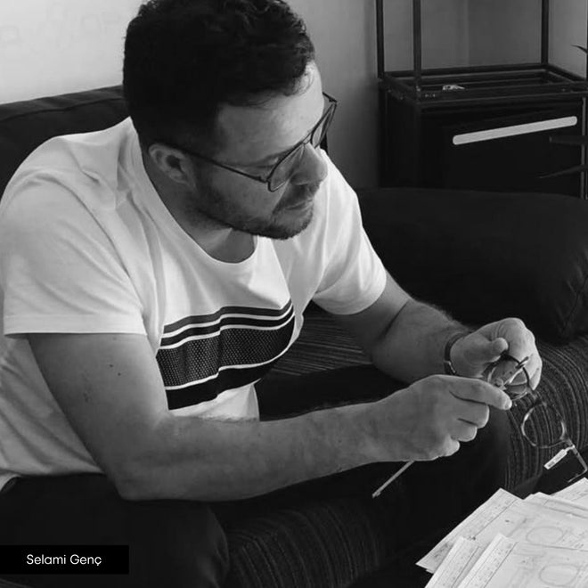 Adam Young markasının üst düzey yetkilisi Selami Genç elinde gözlük ve ölçüm aletiyle çalışıyor.