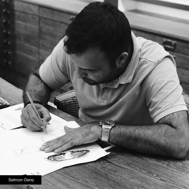 Adam Young markasının üst düzey yetkilisi Selman Genç elinde kalem ve önünde kağıtlar ile çalışıyor.